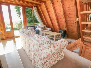 A living room with floral sofas a wooden coffee table and wooden walls at Apple Tree Lodge in Gillingham