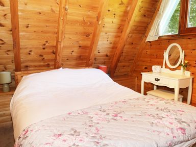 A bedroom with a bed a floral blanket bedside lamps and a dressing table with a mirror at Apple Tree Lodge in Gillingham
