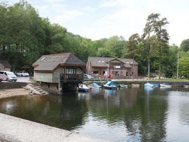 A small lake with boats docked next to two buildings surrounded by trees at Kipling Lodge in Rudyard