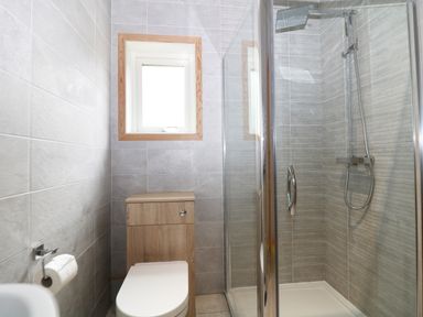 A bathroom with a toilet a glass shower enclosure and a window at Kipling Lodge Rudyard