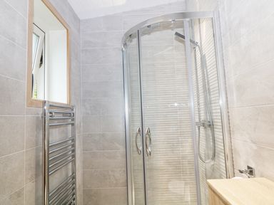 A bathroom with a glass shower enclosure a chrome towel rack and a wooden countertop at Kipling Lodge in Rudyard