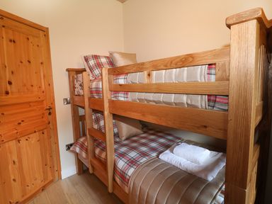 A bedroom with wooden bunk beds and folded towels on the lower bed at Kipling Lodge in Rudyard