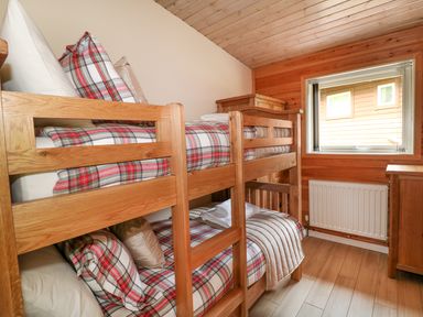 A bedroom with wooden bunk beds plaid bedding a window radiator and wooden furniture at Kipling Lodge in Rudyard
