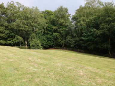 A grassy field with trees in the background at Kipling Lodge in Rudyard
