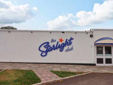The exterior wall of The Starlight Club with an entrance door and an awning in Dawlish Warren