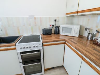 A kitchen corner with a sink stove toaster kettle microwave and utensils at La Capsule in Dawlish Warren
