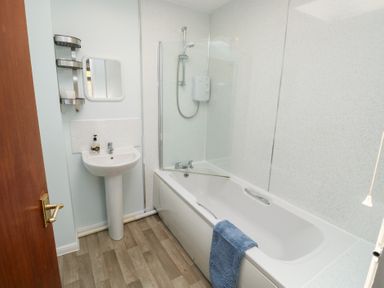 A bathroom with a bathtub a sink a mirror and a wall-mounted shelf at La Capsule Dawlish Warren