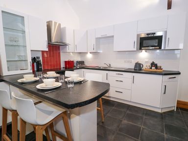 A kitchen with a black countertop and white cabinets at Cornel Glyd in Talybont near Barmouth