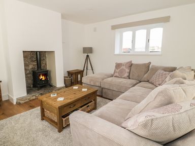 A living room with a beige sectional sofa wooden coffee table and a wood burning stove at 1 Dunkirk Cottages Humshaugh near Hexham