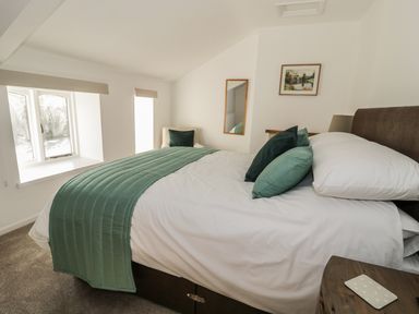 A bedroom with a bed with green pillows and a green throw, a chair in the corner, a mirror and a framed picture on the wall at 1 Dunkirk Cottages Humshaugh near Hexham