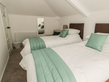 A bedroom with two single beds with white bedding and green cushions at 1 Dunkirk Cottages in Humshaugh near Hexham