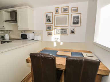 A kitchen area with a wooden dining table and two brown chairs 1 Dunkirk Cottages Humshaugh near Hexham