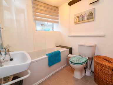 A bathroom with a bathtub sink toilet and wicker laundry basket at Threshings Cottage in Tintagel