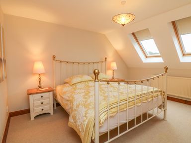 A bedroom with a bed and bedside tables with lamps under skylight windows at Fig Tree Cottage in Bickleigh