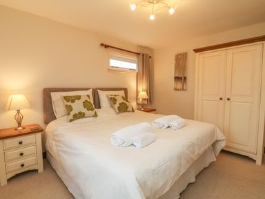 A bedroom with a double bed bedside tables lamps a wardrobe and a window at Fig Tree Cottage in Bickleigh