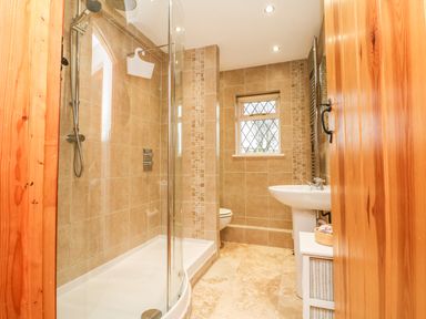 A bathroom with a glass shower enclosure sink toilet window and wooden door at Fig Tree Cottage in Bickleigh
