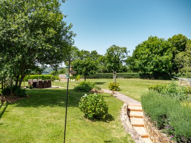 A garden with trees a seating area and a pathway with steps at Fig Tree Cottage in Bickleigh