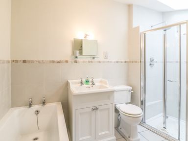A bathroom with a bathtub sink toilet and glass shower enclosure at Tick Tock Cottage in Marnhull