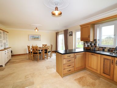 A kitchen and dining area with wooden cabinets dining table and chairs at Benbulben View in Tullaghan County Leitrim