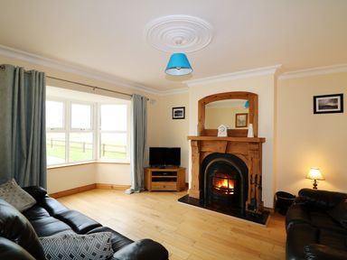 A living room with a fireplace a television and leather sofas at Benbulben View in Tullaghan County Leitrim