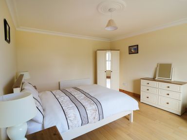 A bedroom with a bed a wardrobe a dresser with a mirror and two lamps at Benbulben View in Tullaghan County Leitrim