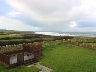 A backyard with a wooden deck stone wall and ocean view at Benbulben View in Tullaghan County Leitrim
