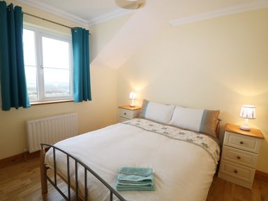 A bedroom with a double bed bedside tables lamps and blue curtains at Benbulben View in Tullaghan County Leitrim