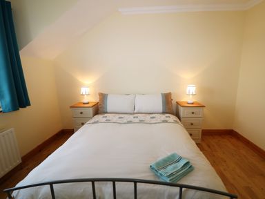 A bedroom with a double bed flanked by two bedside tables with lamps and teal curtains at Benbulben View in Tullaghan County Leitrim