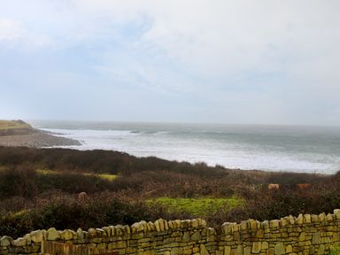 A coastal landscape with a stone wall in the foreground and the sea with waves in the background at Benbulben View in Tullaghan County Leitrim