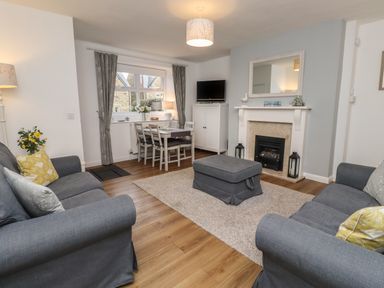 A living room with two sofas a fireplace a dining table and a television at Rose Cottage in Lesbury near Alnmouth