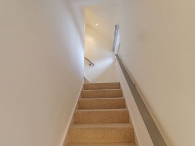 A carpeted staircase with handrails on both sides in a narrow white hallway at Rose Cottage in Lesbury near Alnmouth