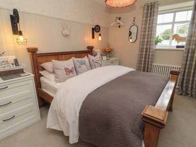 A bedroom with a wooden bed frame and butterfly pillows at The Olde Stables in Warkworth