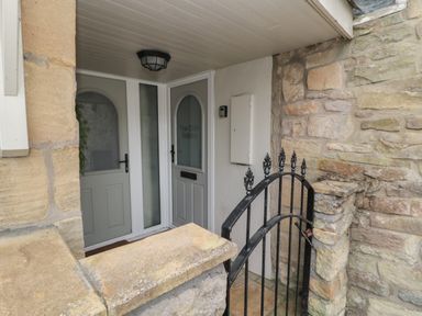 An entrance area with two grey doors and a black metal gate at The Olde Stables in Warkworth