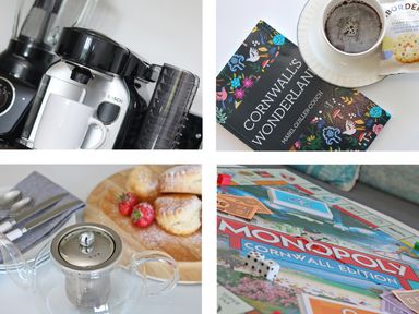 A coffee machine with a cup a book titled Cornwall's Wonderland a teapot with pastries and strawberries and a Monopoly Cornwall Edition board game at Chapel Rock View The Dunes in Perranporth