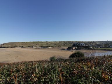A beach with buildings and hills in the background at Chapel Rock View The Dunes in Perranporth