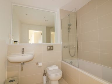 A bathroom with a sink toilet and bathtub with shower at Chapel Rock View The Dunes in Perranporth