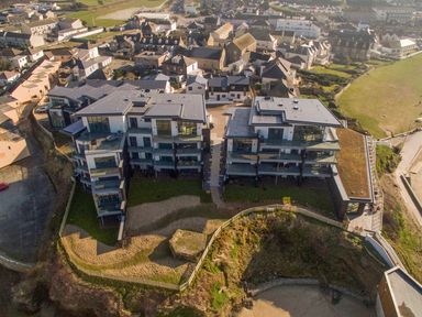Aerial view of two modern apartment buildings overlooking a beach at Chapel Rock View The Dunes in Perranporth