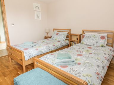 A bedroom with two single beds wooden furniture and folded towels on the beds at The Stable at Church Farm House Limpenhoe near Reedham