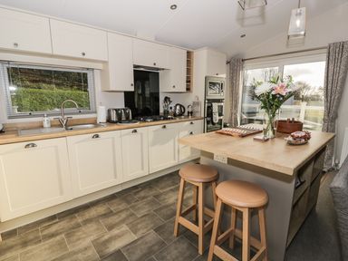 A kitchen with wooden countertops stools and a flower vase at Woodstock Lodge in Wemyss Bay