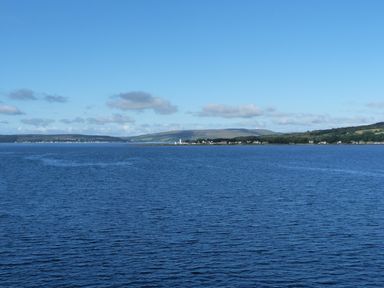 A large body of water with a distant shoreline and hills under a clear blue sky at Woodstock Lodge in Wemyss Bay