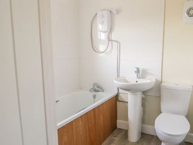 A bathroom with a bathtub shower combination a sink and a toilet at 27 Whitegates in Ludham