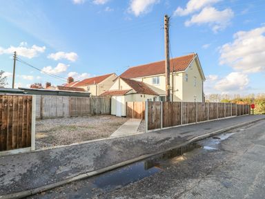 A residential house with a fenced yard and a gravel driveway at 27 Whitegates in Ludham