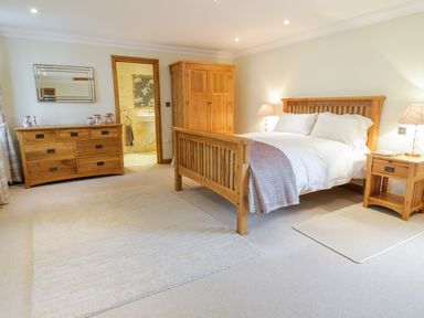 A bedroom with a wooden bed and furniture including a wardrobe and dresser at Pen Y Bryn Cottage in Llandudno