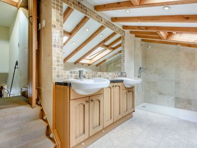 A bathroom with a double sink vanity wooden beams on the ceiling and a walk-in shower at Pen Y Bryn Cottage in Llandudno