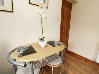 A small wooden table with two stools and a potted white orchid on top at Blaenywawr Annexe in Lampeter
