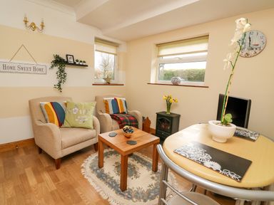 A sitting area with two armchairs a small wooden table and a dining table with chairs at Blaenywawr Annexe in Lampeter