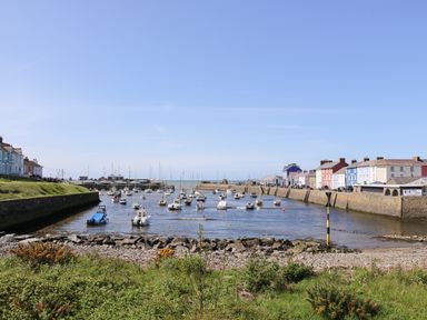 A view of a harbor with boats moored in the water and houses lining the waterfront at Blaenywawr Annexe in Lampeter
