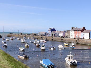 A harbor with boats moored in the water and colorful houses along the quay at Blaenywawr Annexe in Lampeter