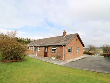A single story brick house with a chimney and multiple windows on a lawn at Blaenywawr in Lampeter