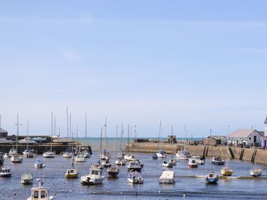 A harbor with boats moored in the water and buildings along the dock at Blaenywawr in Lampeter